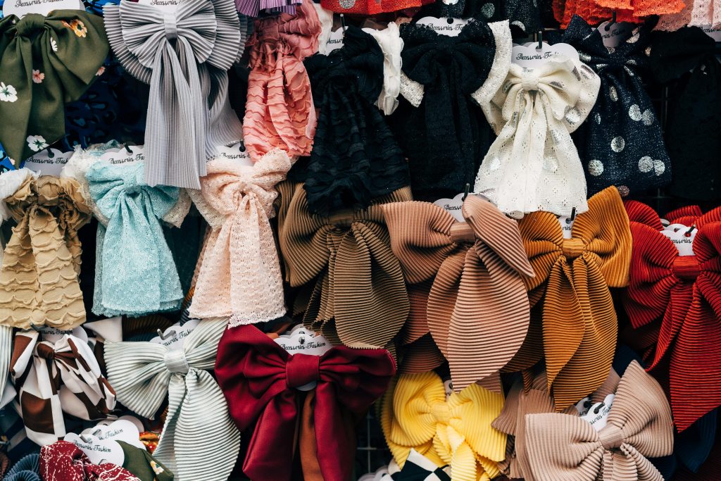A colorful assortment of large, decorative fabric bows displayed for sale at a market.