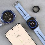 Smartwatch, ring tracker, and smartphone displaying fitness data on a gray surface.